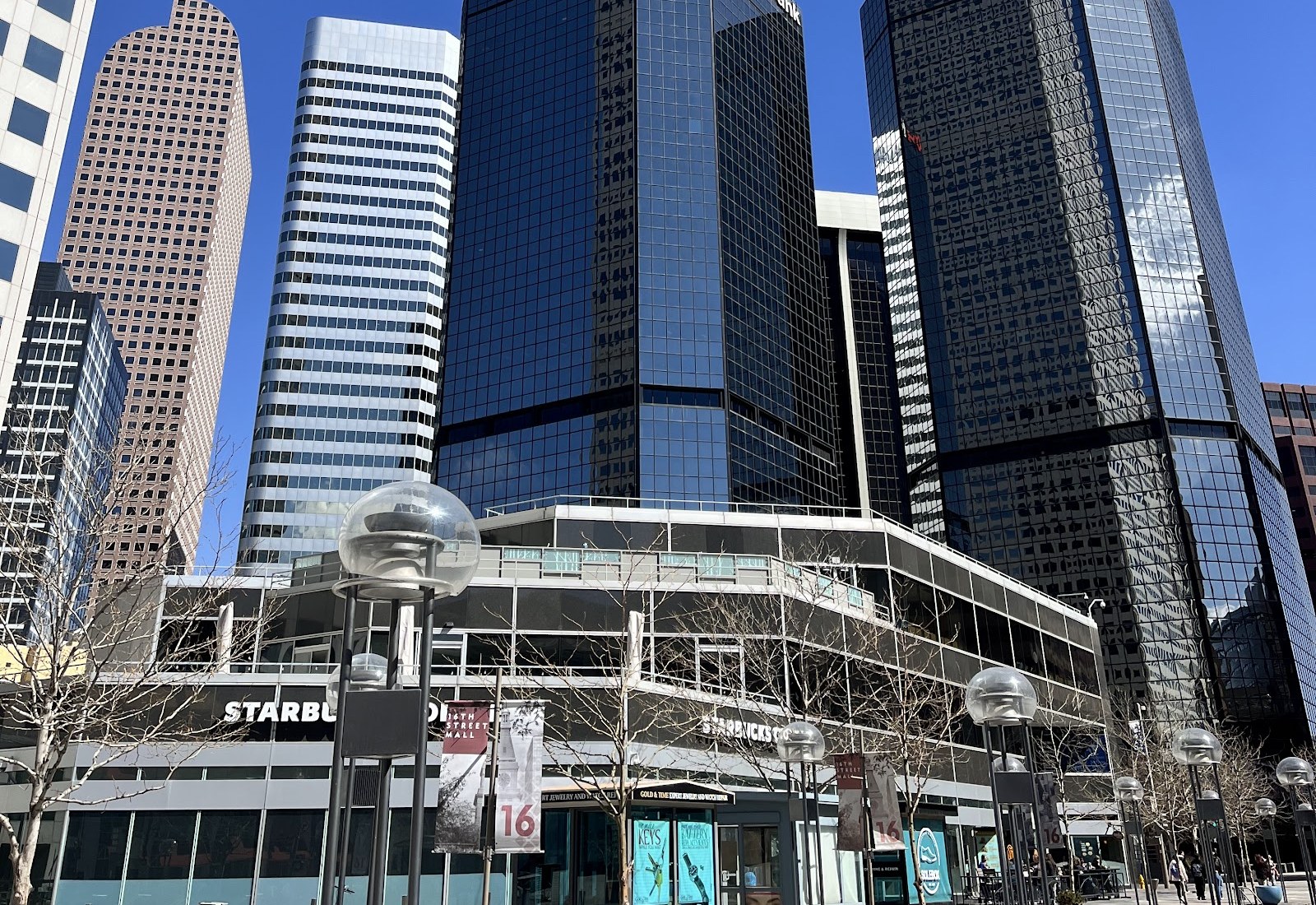 The Gold & Time sign at street level beneath the towers of downtown Denver